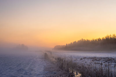 Scenic view of frozen lake against sky during sunset