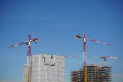 Low angle view of crane at construction site against sky