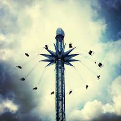 Low angle view of ferris wheel against cloudy sky