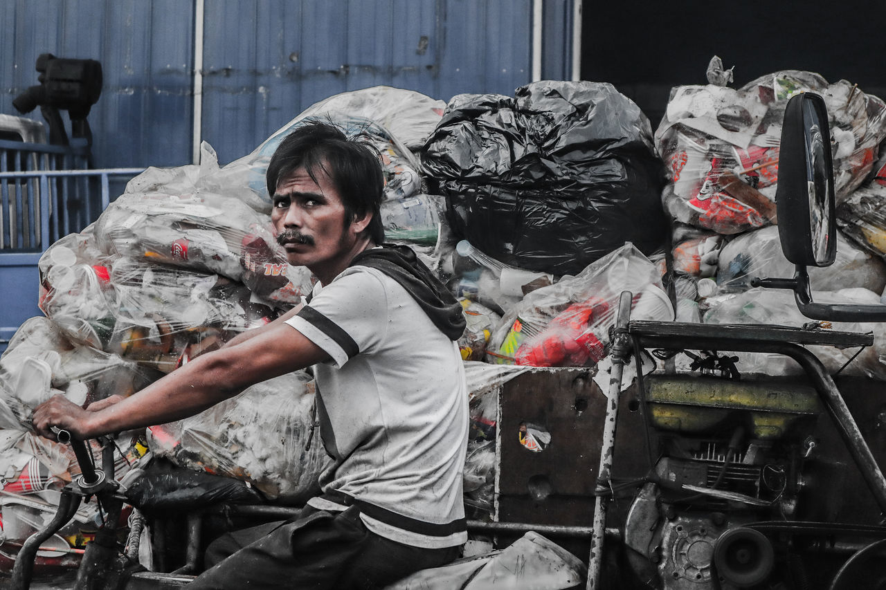 one person, real people, casual clothing, looking at camera, men, lifestyles, young adult, garbage, portrait, day, front view, waist up, standing, indoors, leisure activity, young men, occupation, messy, three quarter length