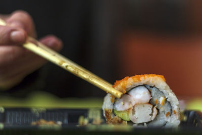 Close-up of a hand holding sushi with chopsticks