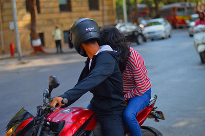 Couple sitting on motorcycle in city