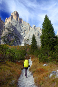 Rear view of man walking on mountain against sky