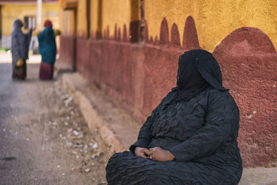 Rear view of man and woman sitting against wall