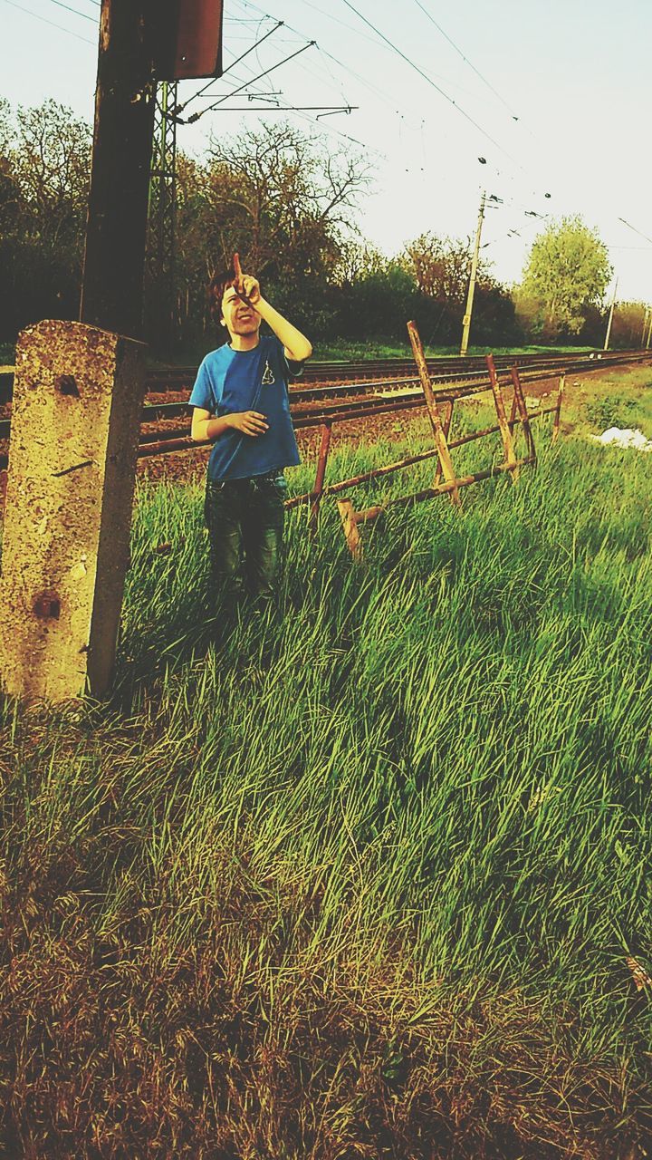 lifestyles, leisure activity, casual clothing, person, young adult, full length, standing, grass, field, young women, three quarter length, tree, sky, holding, plant, front view, growth