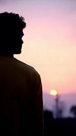 Side view of man standing against sky during sunset