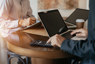 Midsection of man holding coffee cup on table