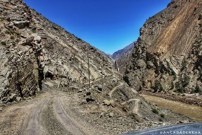 Road by mountains against clear blue sky