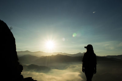 Silhouette woman looking at landscape against sky during sunset