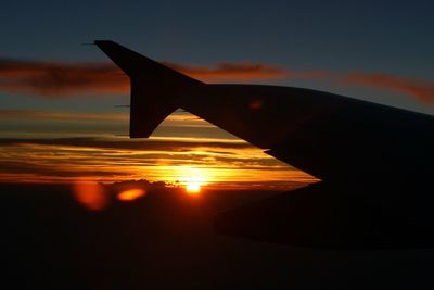 Close-up of silhouette airplane flying over sea during sunset