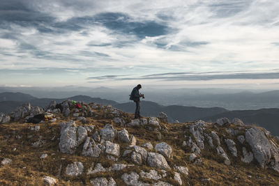 Man standing on rock against sky