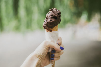 Close-up of cropped hand holding chocolate ice cream cone