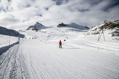 People skiing on snow covered mountains against sky