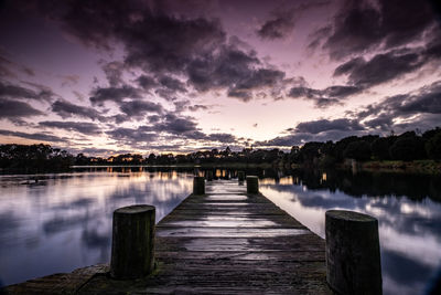 Wooden pier over lake against sky during sunset