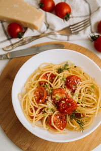 Portion of spaghetti pasta with parmesan and cherry tomatoes sprinkled with spices in a plate