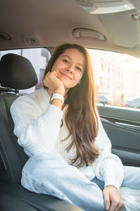 Portrait of young woman sitting in car