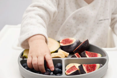 Baby hands taking fruits,berries from silicone plate.child,kid healthy food 