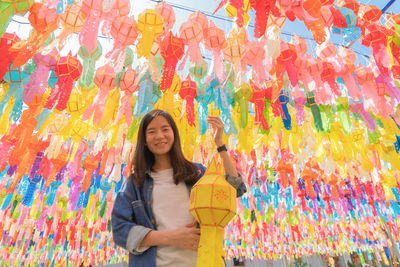 Young woman standing against multi colored wall