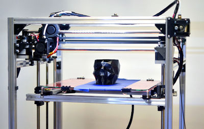 3d printer printing a model in the form of black skull close-up. the 4ht industrial revolution. 
