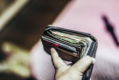 Close-up of man holding wallet with paper currency