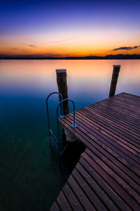 Deck chairs against sea during sunset