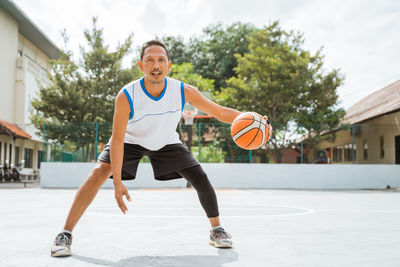 Portrait of man playing with basketball