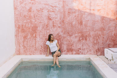 Woman on her 30 s sitting with the foots on the pool  