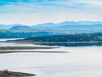 Scenic view of lake by snowcapped mountains against sky