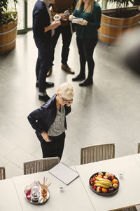 High angle view of mature businesswoman using mobile phone at table in creative office