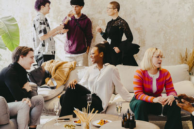 Business colleagues interacting with each other while sitting on sofa during event at convention center