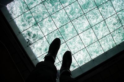 Low section of man standing glass floor