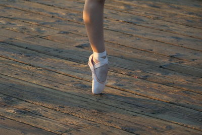 Low section of ballet dancer dancing on hardwood floor