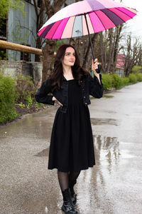 Full length of woman with umbrella walking on road