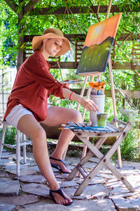 Young female artist working on her art canvas painting outdoors in her garden. art therapy.