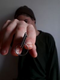 Close-up portrait of man holding keys against wall