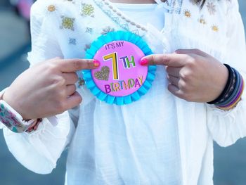 Midsection of girl pointing at badge during birthday