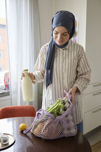 Woman in headscarf unpacking groceries at home