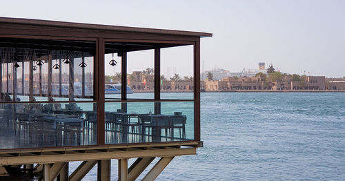 Gazebo in sea against buildings in city against clear sky