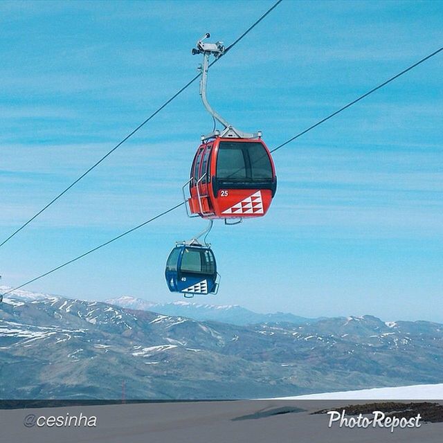 snow, transportation, winter, mountain, cold temperature, mode of transport, overhead cable car, sky, power line, mountain range, communication, season, cable, travel, nature, road sign, ski lift, text, journey, day