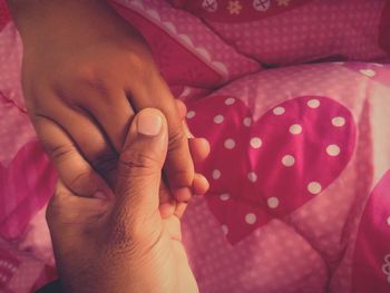 Cropped image of couple holding hands on bed