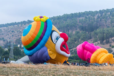 Rear view of multi colored balloons on field against sky