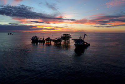 Silhouette boat in sea against sky during sunset