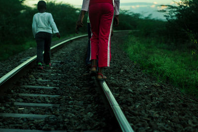 Rear view of people walking on railroad track