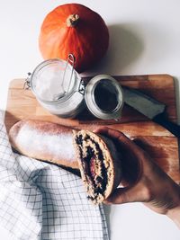 Cropped hand of person holding bread against cutting board