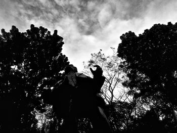 Low angle view of silhouette people against trees against sky