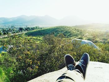 Low section of man on landscape against clear sky