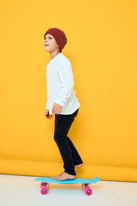 Portrait of young woman standing against yellow background