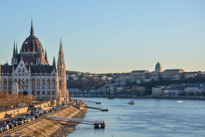 Hungarian parliament building by danube river against clear blue sky