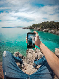 Man photographing on sea against sky