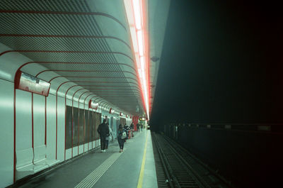 People in illuminated railroad station at night